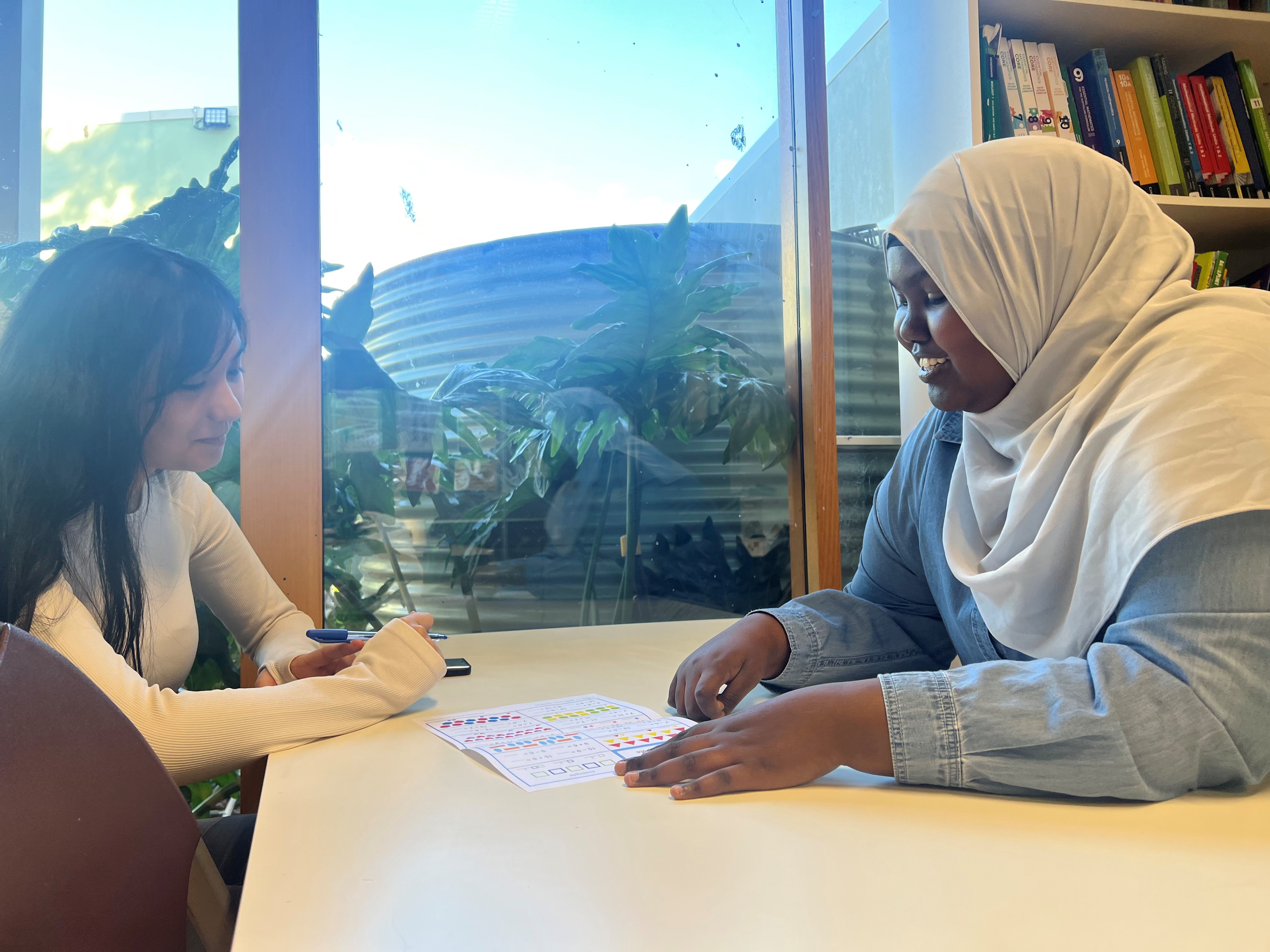 Sumeya (R) is helping a student with her assignement.