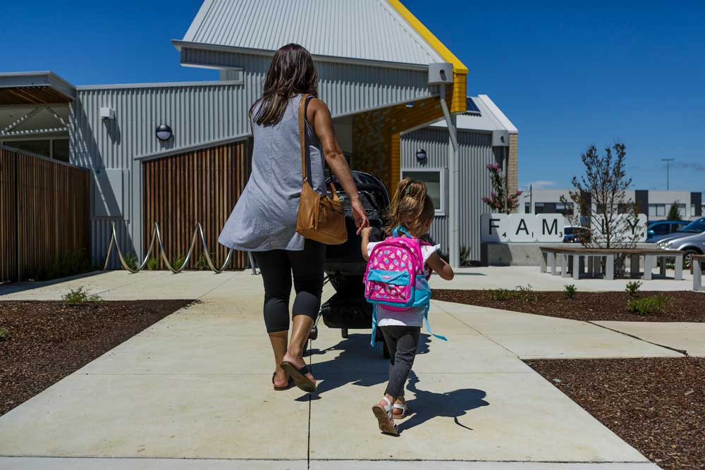 Mother and daughter walking into school. The school entrance is in the background.