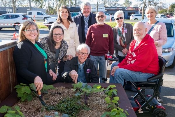 Photo of several people gathered around a garden bed