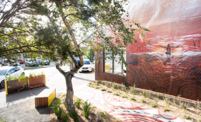 Aboriginal mural on wall beside newly landscaped path with trees and garden beds