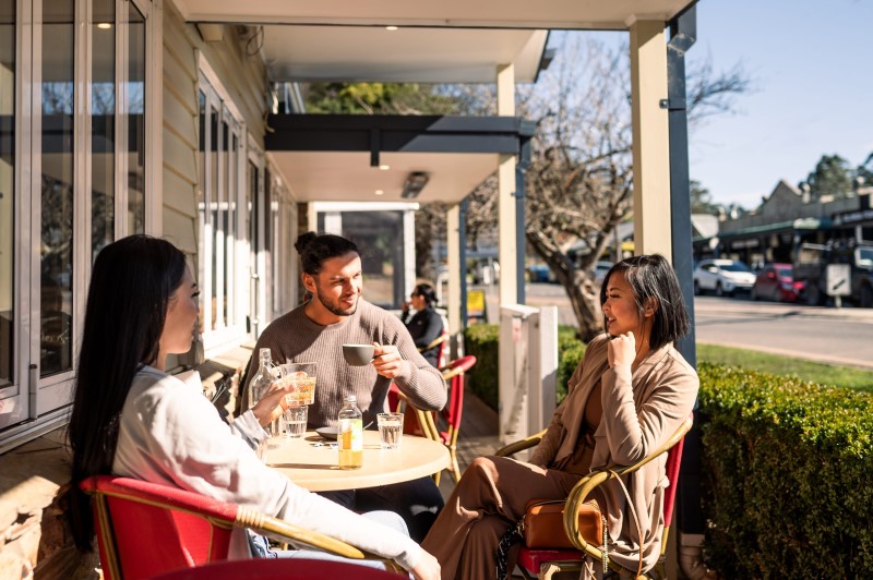 Three friends are sitting in an outdoor cafe and enjoying drinks.