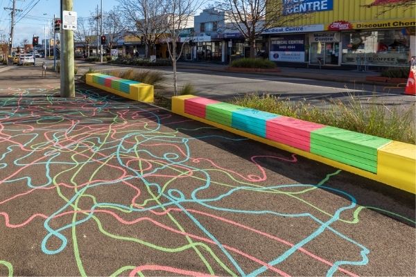 Colourful drawings on the pavement in several colours. The lines move in flowing shapes.